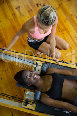 Trainer assisting woman with pilates on reformer