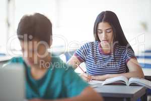 Attentive schoolgirl studying in classroom