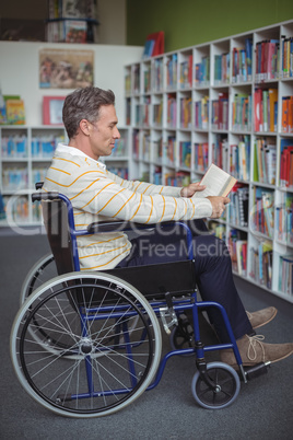 Attentive disabled school teacher reading book in library