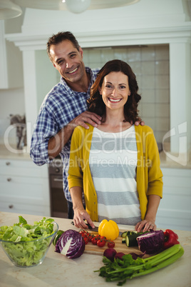 Happy couple chopping vegetables in kitchen