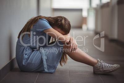 Sad schoolgirl sitting in corridor