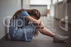 Sad schoolgirl sitting in corridor