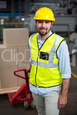 Factory worker pulling trolley of cardboard boxes in factory