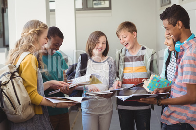 Group of smiling students standing with notebook in corridor