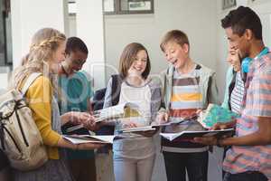 Group of smiling students standing with notebook in corridor