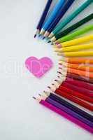Colored pencils arranged in semi circle with heart on white background