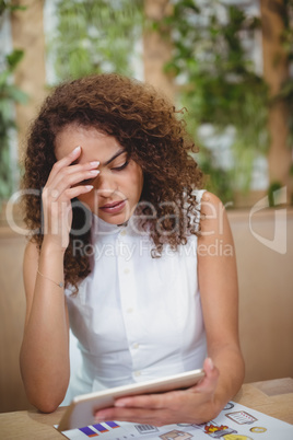 Worried female executive holding digital tablet