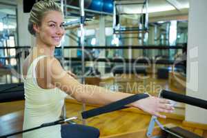 Portrait of happy woman practicing stretching exercise on reformer