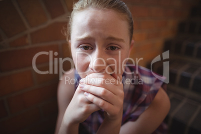 Portrait of sad schoolgirl sitting alone on staircase