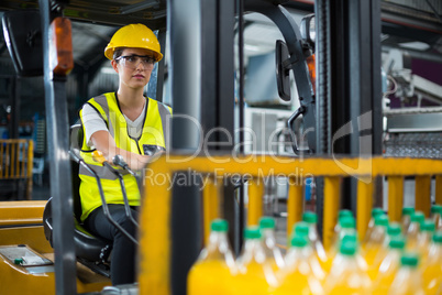 Female factory worker driving forklift in factory