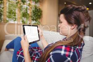 Female executive relaxing on sofa and using digital tablet
