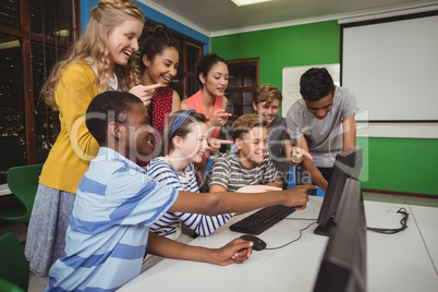 Smiling students studying together in computer classroom