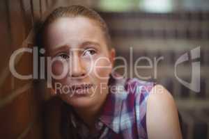 Sad schoolgirl sitting alone on staircase