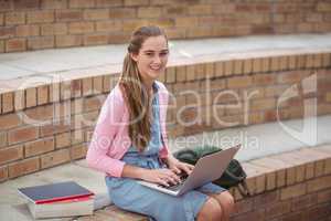 Portrait of schoolgirl using laptop in campus