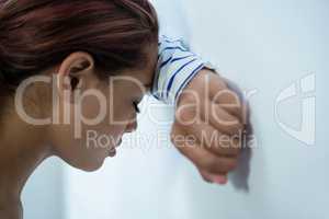 Stressed woman leaning on wall