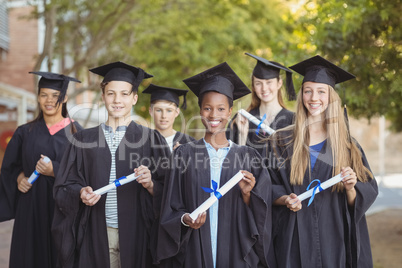 Portrait of graduate school kids standing with degree scroll in campus
