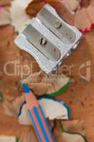 Close-up of sharpener and colored pencil with shavings