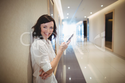 Portrait of female business executive using mobile phone in corridor