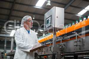 Factory engineer maintaining record on clipboard in factory