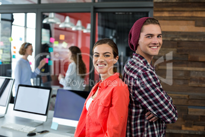 Smiling business executive standing back to back in office