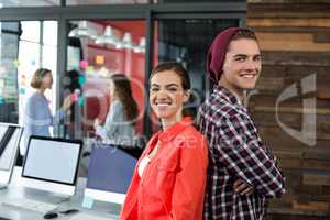 Smiling business executive standing back to back in office