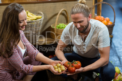 Man and woman vendors holding potatoes and tomatoes