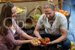 Man and woman vendors holding potatoes and tomatoes