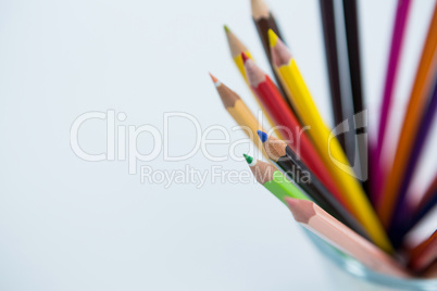 Colored pencils kept in glass on white background