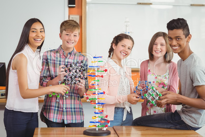 Portrait of happy students experimenting molecule model in laboratory