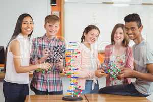 Portrait of happy students experimenting molecule model in laboratory