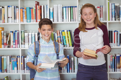 Portrait of happy students holding books in library