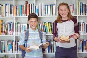 Portrait of happy students holding books in library