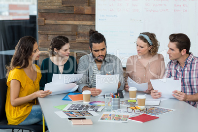 Graphic designers discussing over document in meeting