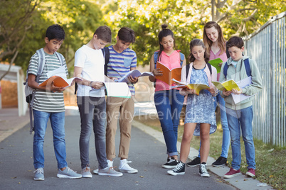 School kids reading books on road in campus
