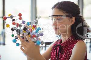 Attentive schoolgirl experimenting molecule model in laboratory