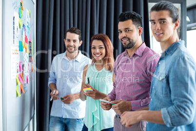 Portrait of business executives standing with sticky notes and marker