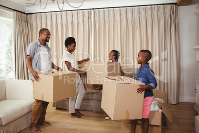 Parents and kids holding cardboard boxes in living room