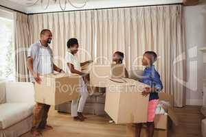 Parents and kids holding cardboard boxes in living room
