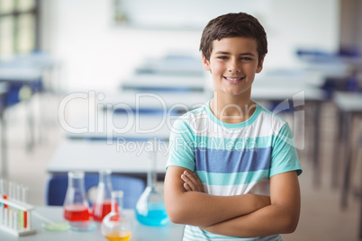 Portrait of schoolboy standing with arms crossed in laboratory