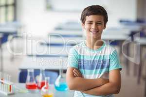 Portrait of schoolboy standing with arms crossed in laboratory