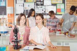 Portrait of students experimenting on microscope in laboratory
