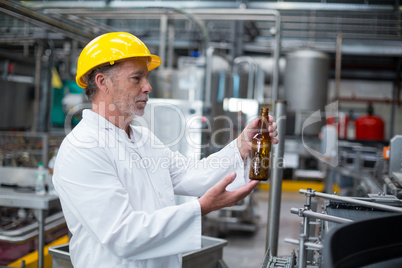 Factory worker examining a bottle in factory