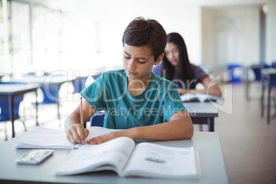 Schoolboy doing homework in classroom