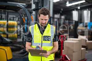 Factory worker writing on clipboard in factory