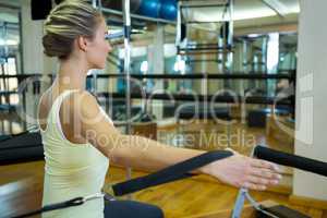 Determined woman practicing stretching exercise on reformer