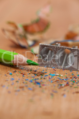 Close-up of sharpener and colored pencil with shavings