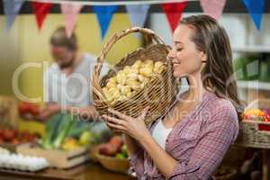 Woman vendor holding a basket if potatoes in grocery store