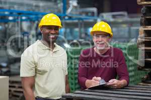 Two factory workers standing with clipboard in drinks production plant