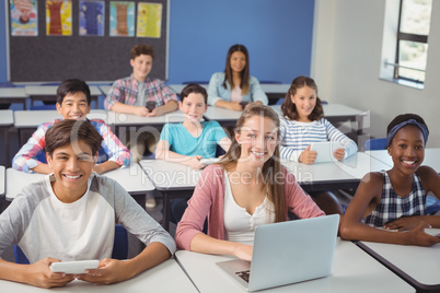 Students with digital tablet and laptop in classroom