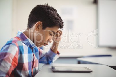 Schoolboy using digital tablet at desk